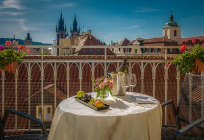a table with a bowl of fruit and flowers on a balcony at Grand Hotel Bohemia in Prague