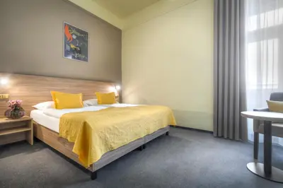 a bedroom with a bed with yellow sheets and a window at Atlantic Hotel in Prague