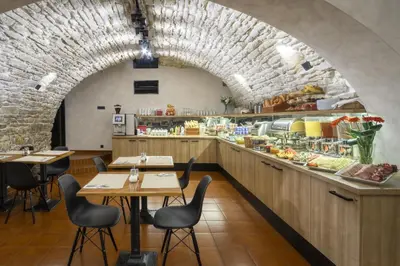 a restaurant with tables and a counter with food at Hotel Mucha in Prague