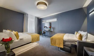 a hotel room with two beds and a desk at Hotel Mucha in Prague