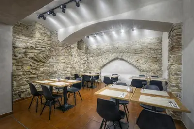 a restaurant with wooden tables and chairs in front of a stone wall at Hotel Mucha in Prague