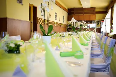 a long row of tables with green napkins and glasses at Hotel Grand in Řevnice
