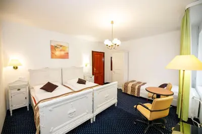 a bedroom with a bed and a desk and a table at Hotel Grand in Řevnice
