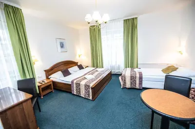 a hotel room with two beds and a table at Hotel Grand in Řevnice