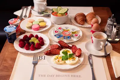 a table with plates of breakfast foods and cups of coffee at The Charles in Prague