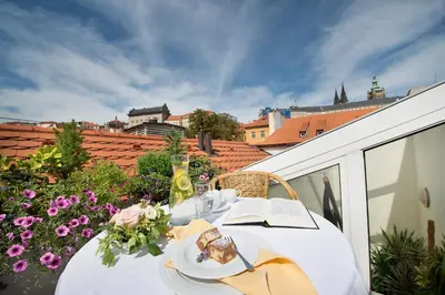 a table with plates of food on a balcony with flowers at Boutique Hotel Constans in Prague