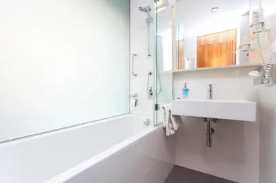 a white bathroom with a sink and a shower at Hotel Carol in Prague