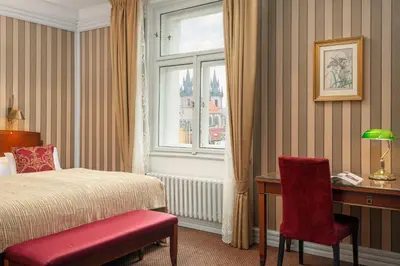 a bedroom with a bed and a desk and a window at Hotel Paris Prague in Prague