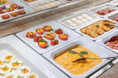 a buffet of food with eggs and tomatoes in trays at Hotel Paris Prague in Prague