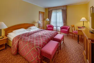 a hotel room with a large bed and chairs at Hotel Savoy Prague in Prague