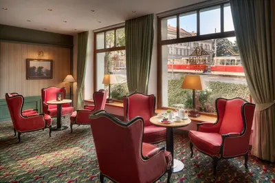 a waiting room with red chairs and tables and a window at Hotel Savoy Prague in Prague