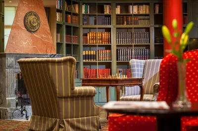 a library with two chairs and a table with books at Hotel Savoy Prague in Prague