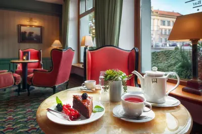 a table with a piece of cake and a cup of tea at Hotel Savoy Prague in Prague