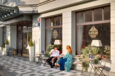 two people sitting at tables outside of a building at Hotel Savoy Prague in Prague