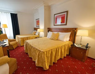 a hotel room with two beds and a chair at Hotel Bologna in Prague