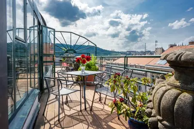 a balcony with chairs and a table with flowers at Hotel Bologna in Prague