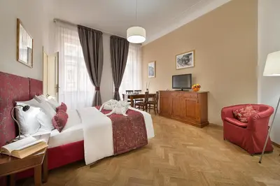 a bedroom with a bed and a chair and a television at Hotel Suite Home Prague in Prague