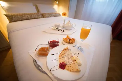 a table with a plate of food and a glass of orange juice at Hotel Suite Home Prague in Prague