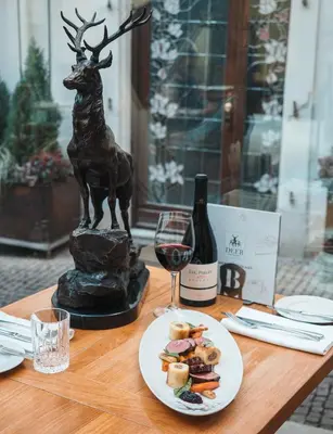 a table with a plate of food and a wine glass at Iron Gate Hotel & Suites Prague by BHG in Prague