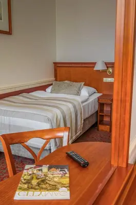 a bedroom with a bed and a table with a remote control at Adria Hotel Prague in Prague