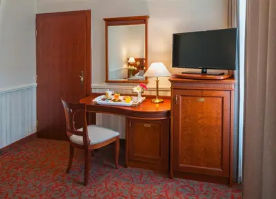 a hotel room with a desk with a television and a table with a chair at Adria Hotel Prague in Prague