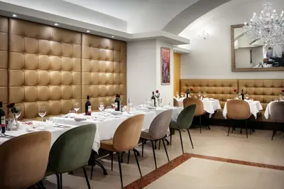 a restaurant with white tables and chairs and a large wall at Kosher Hotel King David Prague in Prague