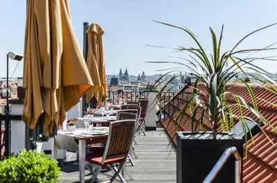 a patio with tables and chairs and umbrellas at Aria Hotel Prague in Prague