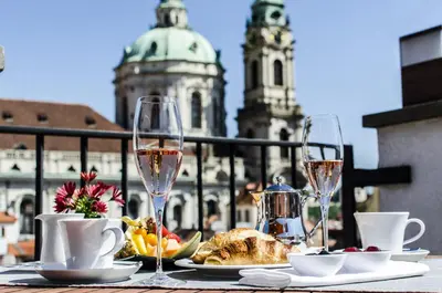 a table with wine glasses and food on a balcony at Aria Hotel Prague in Prague