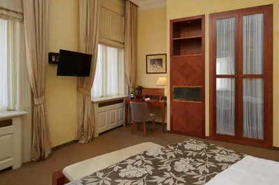 a hotel room with a bed and a desk and a television at Ventana Hotel Prague in Prague