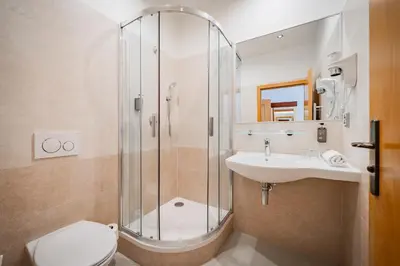a bathroom with a shower and a toilet and a sink at Hotel Atos in Prague