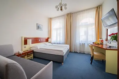 a hotel room with a bed and a desk at Hotel Atos in Prague