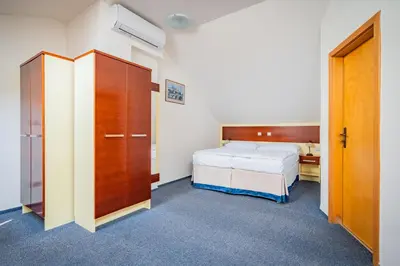 a bedroom with a bed and a wooden cabinet and a bed at Hotel Atos in Prague