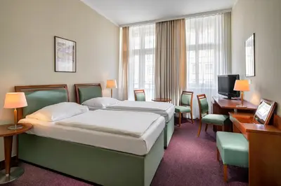 a hotel room with two beds and a desk and chairs at Clarion Hotel Prague Old Town in Prague