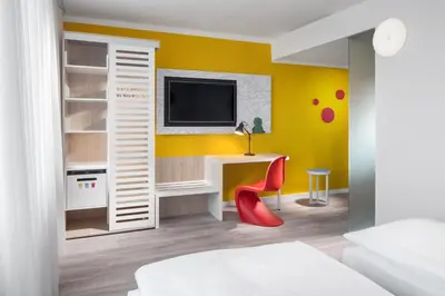 a bedroom with a desk and a tv on a yellow wall at Comfort Hotel Prague City in Prague