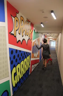 a woman is walking down a hallway with colorful walls at Comfort Hotel Prague City in Prague