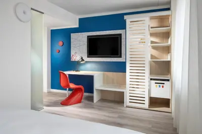 a room with a desk with a tv and a red chair at Comfort Hotel Prague City in Prague