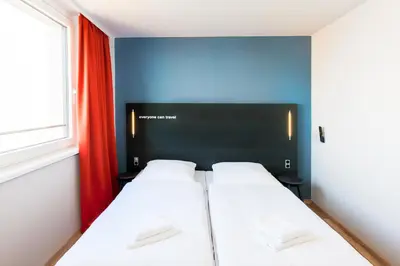 two beds in a small room with a window at a&o Prague Rhea in Prague