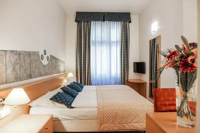 a hotel room with a bed and a vase of flowers at Hotel Tivoli Prague in Prague