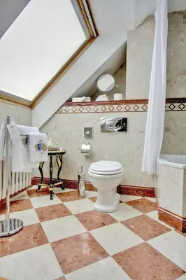 a bathroom with a toilet and a checkered floor at Alchymist Grand Hotel and Spa in Prague
