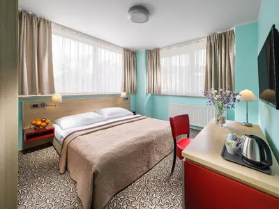 a hotel room with a bed and a desk and window at Hotel Michael in Prague