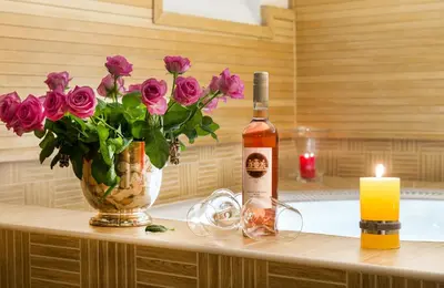 a bottle of wine and a vase of flowers and a candle at Boutique Hotel Seven Days in Prague