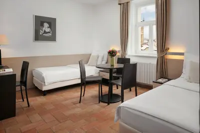 a hotel room with two beds and a table and chairs at Hotel Praga 1 in Prague