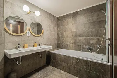 a bathroom with a sink and a tub and mirrors at Quite Loft with Balcony and 3 Air Conditioners in Prague