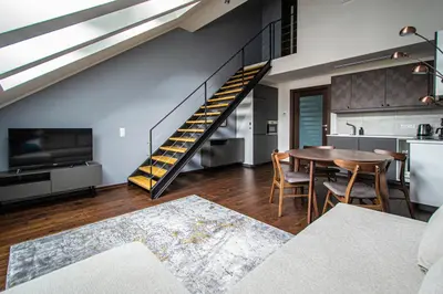 a living room with a table and a staircase at Quite Loft with Balcony and 3 Air Conditioners in Prague