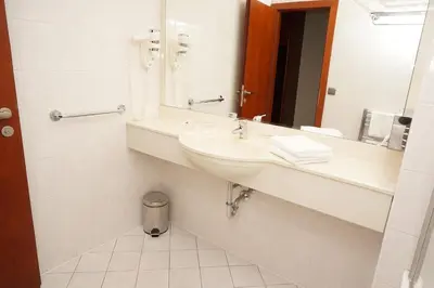 a white bathroom with a sink and a mirror at Hotel Coronet in Prague