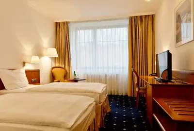 a hotel room with two beds and a television at Hotel Coronet in Prague