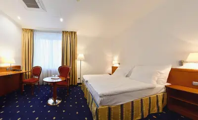 a hotel room with a bed and a table and chairs at Hotel Coronet in Prague