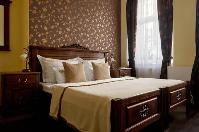 a bedroom with a bed with a wooden headboard and a window at Hotel Residence U Černého Orla in Prague