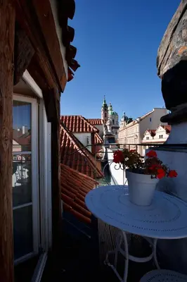 a table on a balcony with a pot of flowers at Hotel Residence U Černého Orla in Prague