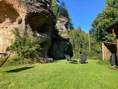 two chairs sitting in the grass near a rock formation at Wellness Kokořín in Kokořín